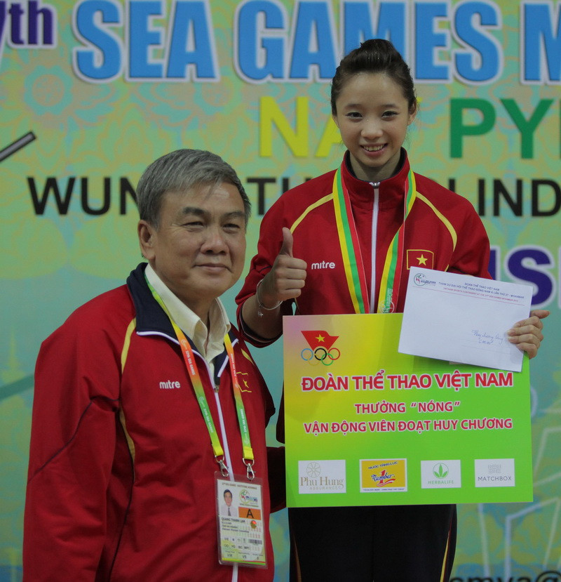Ông Lâm Quang Thành, Trưởng đoàn thể thao Việt Nam trao thưởng nóng cho Dương Thúy Vy ngay sau khi vận động viên này đoạt Huy chương Vàng. (Ảnh: Quang Nhựt/TTXVN)