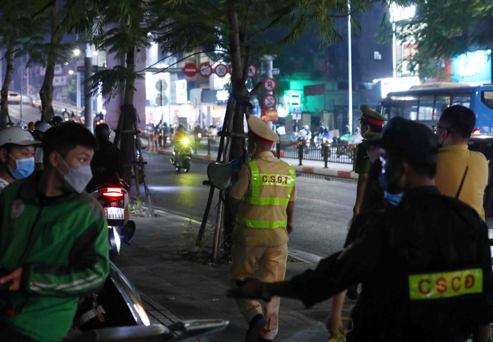 Lực lượng chức năng phải hết sức vất vả yêu cầu đám đông giải tán tại khu vực xung quanh tổ công tác 141 làm nhiệm vụ. (Ảnh: Phạm Kiên/TTXVN)