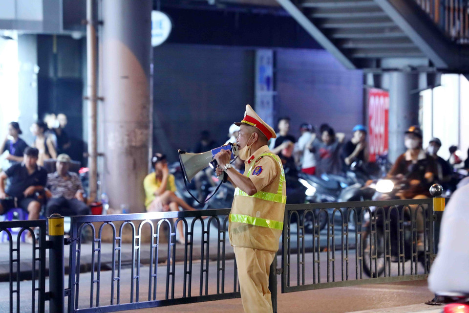 Lực lượng Cảnh sát Giao thông phải dùng loa yêu cầu giải tán đám đông gây ảnh hưởng đến tổ công tác 141 làm nhiệm vụ tại phố Chùa Bộc, quận Đống Đa. (Ảnh: Phạm Kiên/TTXVN)