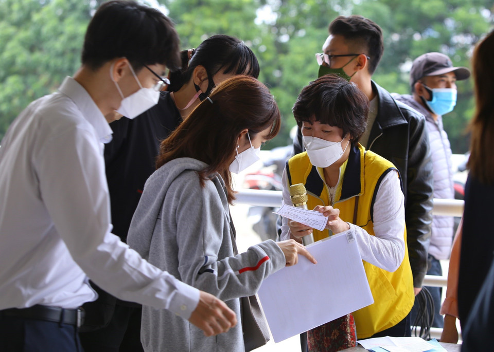 Những công dân Hàn Quốc được tình nguyện viên hỗ trợ tại điểm tiêm Sân vận động Mỹ Đình. (Ảnh: Hoàng Hiếu/TTXVN)