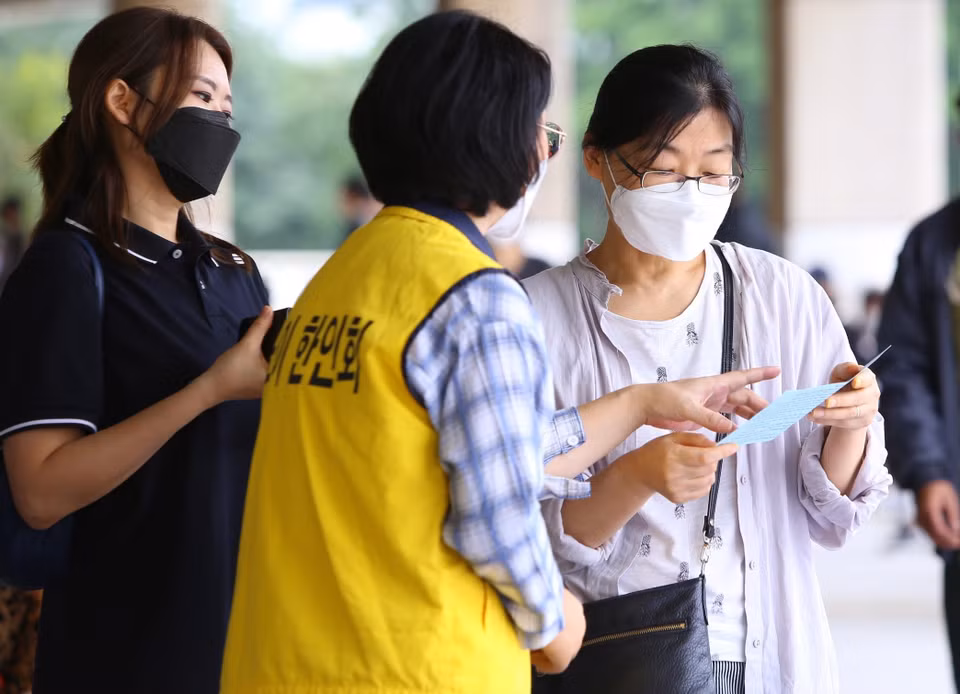  Những công dân Hàn Quốc được tình nguyện viên hỗ trợ tại điểm tiêm Sân vận động Mỹ Đình. (Ảnh: Hoàng Hiếu/TTXVN)