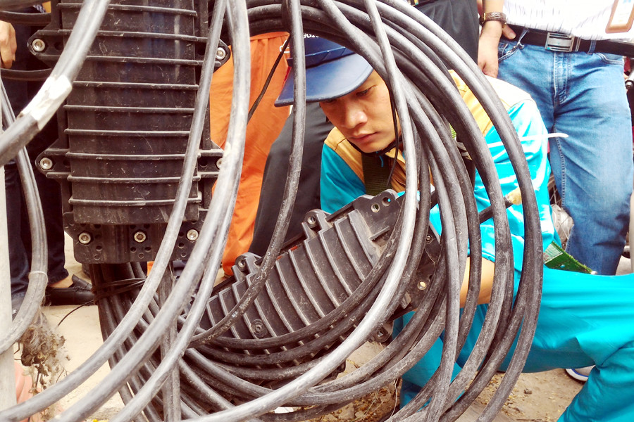 Nhiều dây cáp vẫn được bó tròn ở dưới chân cột điện, gây mất mỹ quan và nguy hiểm cho người đi lại. (Ảnh: Trung Hiền/Vietnam+)