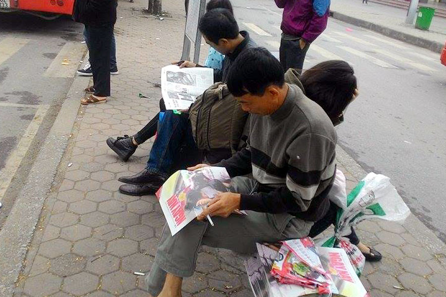 Với nhiều người ngồi chờ xe buýt, việc được phát một tờ báo sẽ giúp họ ​'tiêu' khoảng thời gian vô ích. (Ảnh: CTV/Vietnam+)