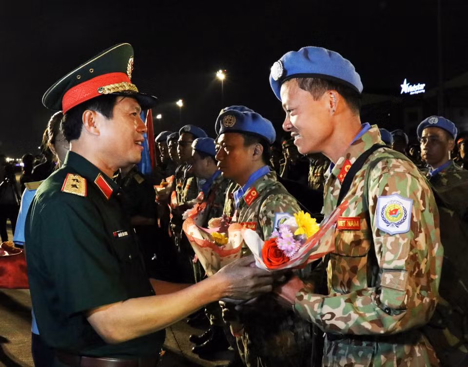 Trung tướng Nguyễn Tân Cương, Phó Tổng tham mưu trưởng Quân đội nhân dân Việt Nam (trái) tặng hoa chúc mừng các cán bộ, chiến sỹ Bệnh viện dã chiến cấp 2 số 1 trở về nước trong đợt này. (Ảnh: Xuân Khu/TTXVN)