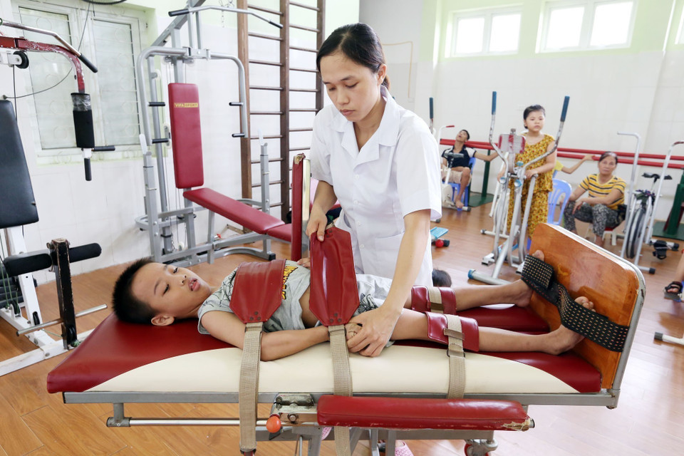 Kỹ thuật viên Trung tâm Phục hồi chức năng người khuyết tật Thụy An (thuộc Bộ Lao động-Thương binh và Xã hội) điều trị phục hồi chức năng cho trẻ em khuyết tật. (Ảnh: Anh Tuấn/TTXVN)