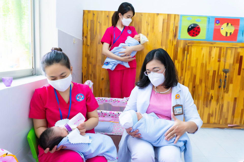 Bảo mẫu và bác sỹ Bệnh viện Hùng Vương cùng chăm sóc trẻ sơ sinh có mẹ mắc COVID-19 chờ người thân đón về. (Ảnh: TTXVN phát)