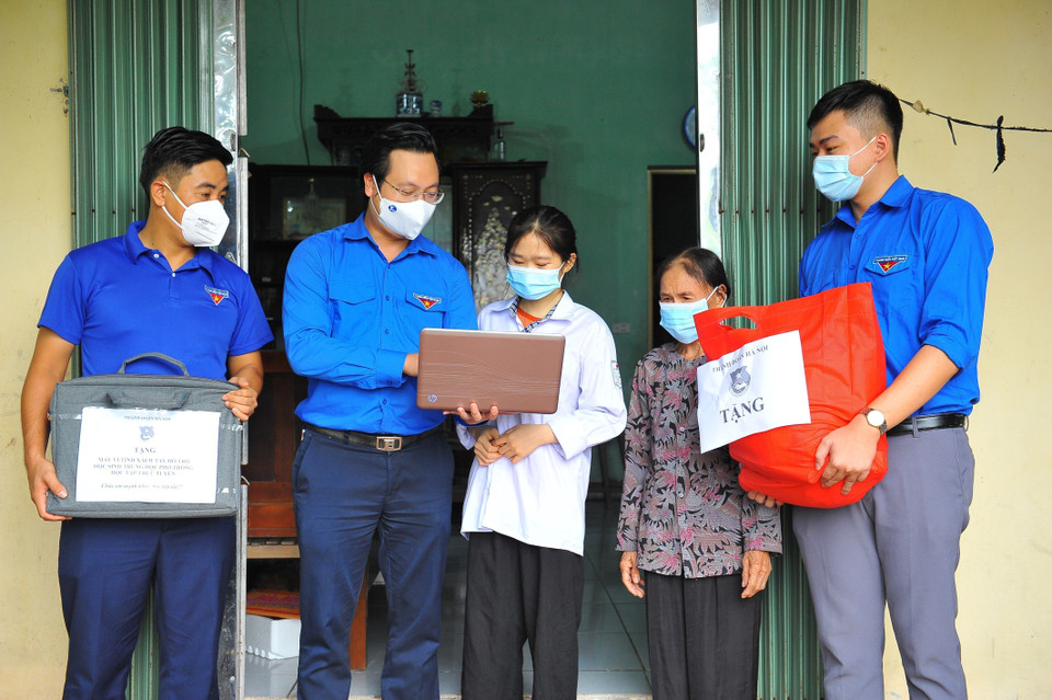 Phó Bí thư Thành đoàn Hà Nội Trần Quang Hưng trao tặng máy tính và túi an sinh cho cháu Trần Thị Thanh Chúc (huyện Thường Tín) có hoàn cảnh khó khăn, thiếu thiết bị học online. (Ảnh: Minh Đức/TTXVN)
