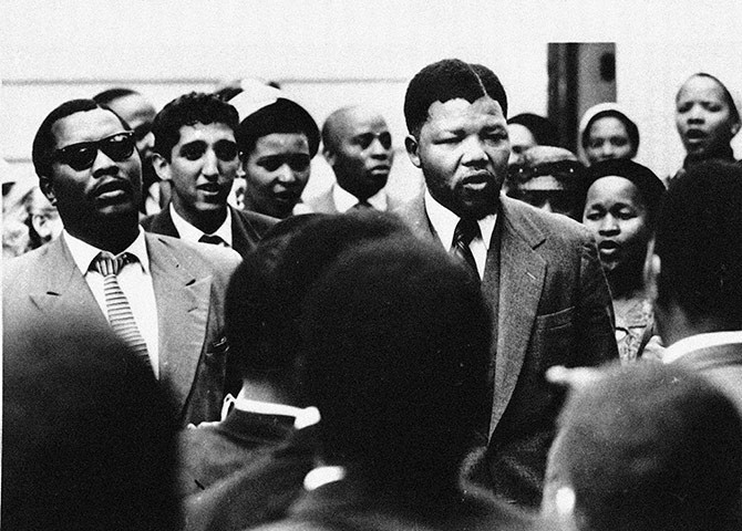 Năm 1956: Mandela hát với những người ủng hộ mình trong một phiên tòa xét xử ông phạm tội phản quốc. Sau quá trình xét xử kéo dài từ năm 1956-1961, ông và 150 người bị xử tội phản quốc trước đó được tuyên trắng án. (Nguồn: AP)