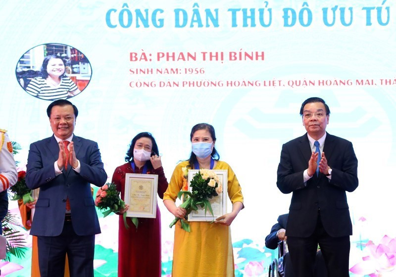 Bí thư Thành ủy Hà Nội Đinh Tiến Dũng và Chủ tịch UBND thành phố Hà Nội Chu Ngọc Anh trao tặng danh hiệu “Công dân Thủ đô ưu tú” năm 2021 cho bà Phan Thị Bính, công dân phường Hoàng Liệt, quận Hoàng Mai, Hà Nội. (Ảnh: Nguyễn Điệp/TTXVN)