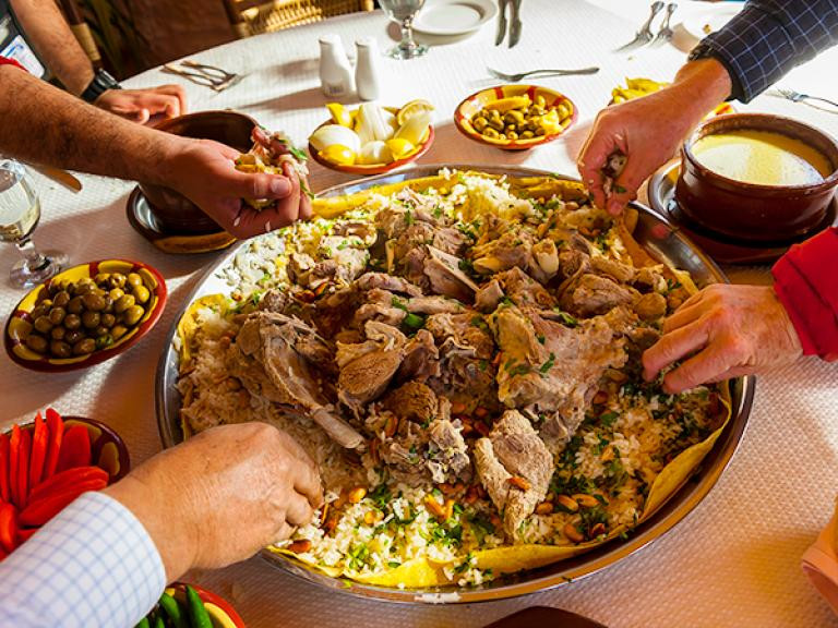 Thưởng thức món ăn truyền thống của Jordan, đặc biệt là món mansaf gồm thịt cừu hoặc dê nấu trong sữa chua và ướp với các loại thảo mộc thơm và gia vị, sau đó rắc hạnh nhân và một số loại hạt. (Nguồn: NatGeo)