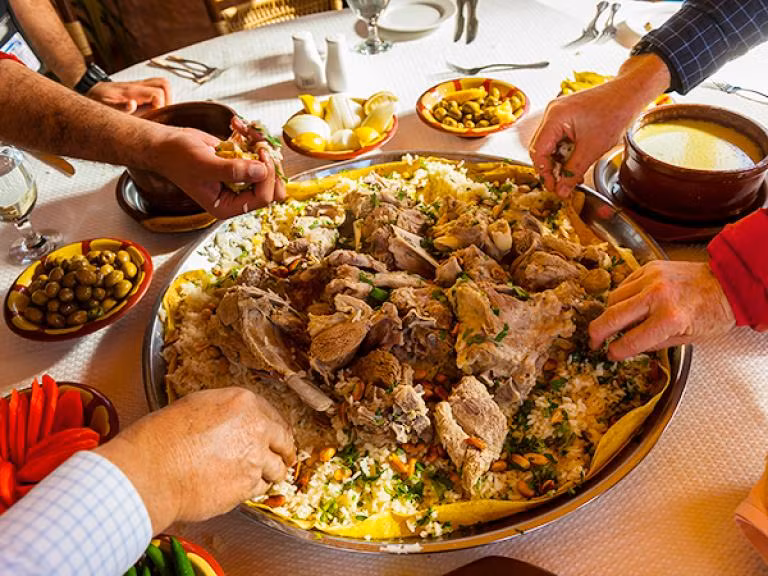 Thưởng thức món ăn truyền thống của Jordan, đặc biệt là món mansaf gồm thịt cừu hoặc dê nấu trong sữa chua và ướp với các loại thảo mộc thơm và gia vị, sau đó rắc hạnh nhân và một số loại hạt. (Nguồn: NatGeo)