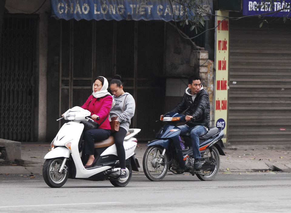 Đi xe máy du xuân không đội mũ bảo hiểm trên phố Trần Khát Chân. (Ảnh: Minh Đức/TTXVN)