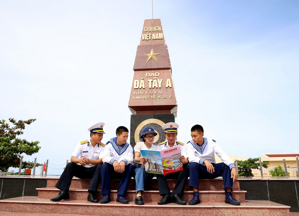 Những người lính Trường Sa đọc báo từ đất liền gửi tặng dưới chân Cột mốc chủ quyền Đảo Đá Tây A. (Ảnh: Hồng Đạt/TTXVN)
