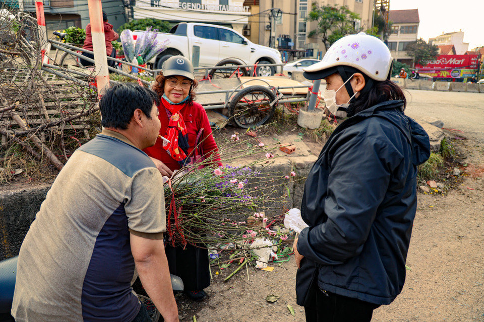 Cô Phương (quận Tây Hồ) vừa mua được cành đào ưng ý giá 150.000 đồng. “Năm nào tôi cũng đi mua cành đào sớm về chơi Tết dương trước cho có không khí, đến khi gần Tết Âm lịch thì lại đi mua tiếp sau,” cô nói. (Ảnh: Minh Hiếu/Vietnam+)