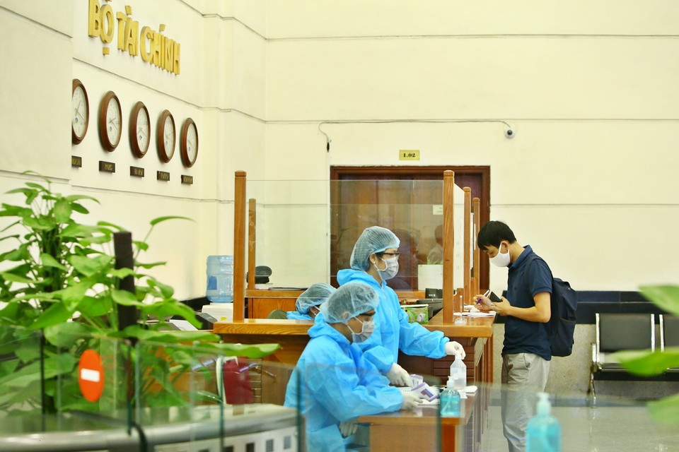 Khi đến liên hệ công tác tại Bộ Tài chính, khách phải điền thông tin vào tờ khai và thực hiện đeo khẩu trang, đo thân nhiệt trước khi vào cơ quan. (Ảnh: Minh Quyết/TTXVN)