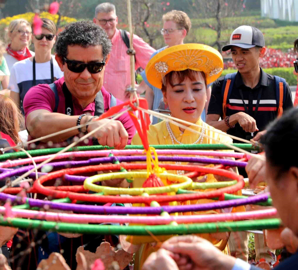 Du khách quốc tế cùng tham gia vào lễ dựng cây nêu ngày Tết tại Khu Di sản thế giới Hoàng thành Thăng Long (Hà Nội). (Ảnh: Thanh Tùng/TTXVN)