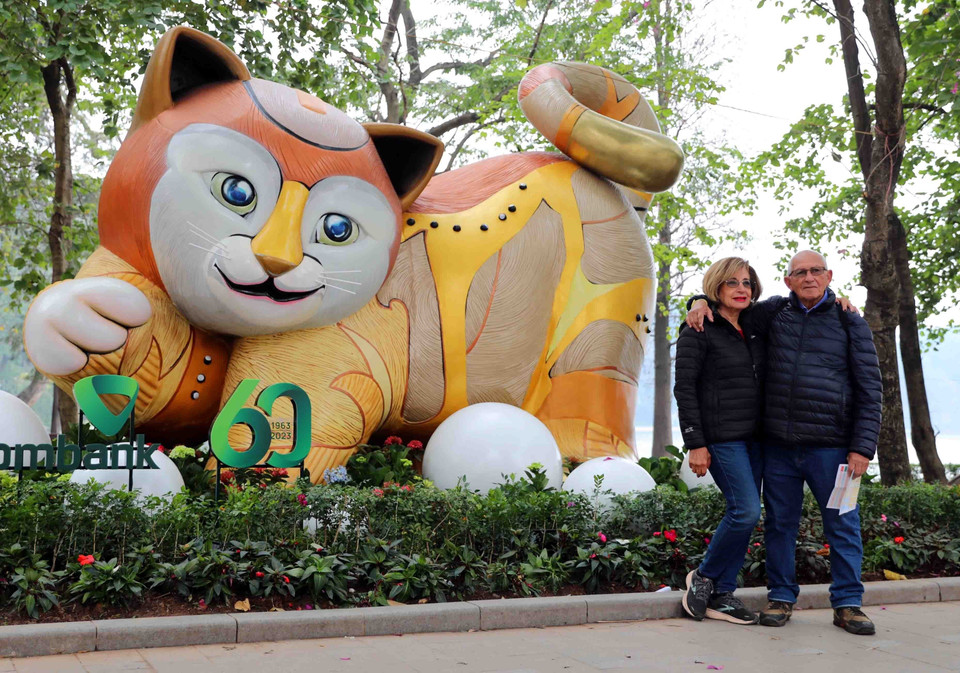 Du khách quốc tế hứng thú chụp ảnh cùng hình tượng mèo, linh vật năm Quý Mão 2023 bên hồ Gươm. (Ảnh: Thanh Tùng/TTXVN)