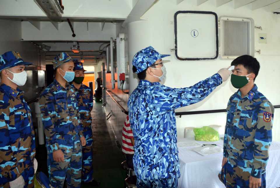 Kiểm tra thân nhiệt từng người trước khi lên tàu đi làm nhiệm vụ. (Ảnh: TTXVN phát)