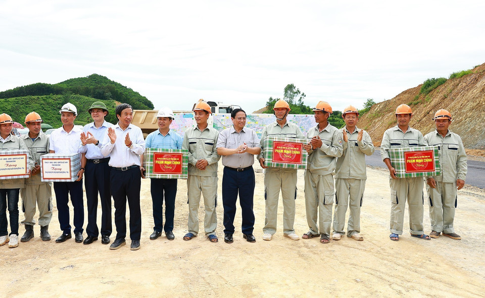 Thủ tướng Phạm Minh Chính tặng quà cho công nhân thi công Dự án xây dựng tuyến đường Đông-Tây. (Ảnh: Dương Giang/TTXVN)
