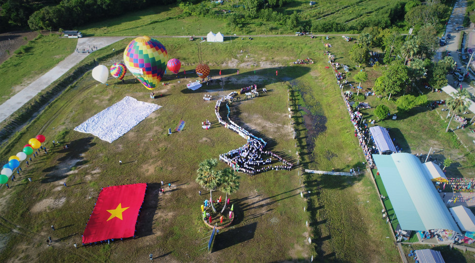 Hơn 600 người thuộc các tầng lớp, đại diện cho khối đại đoàn kết toàn dân tộc trên địa bàn huyện Tri Tôn xếp thành hình bản đồ Việt Nam và 11 khinh khí cầu loại nhỏ với đường kính gần 3m kéo đại kỳ rộng 200m2 đưa lên độ cao 50m trên bầu trời vùng Bảy núi An Giang. (Ảnh: Công Mạo/TTXVN)