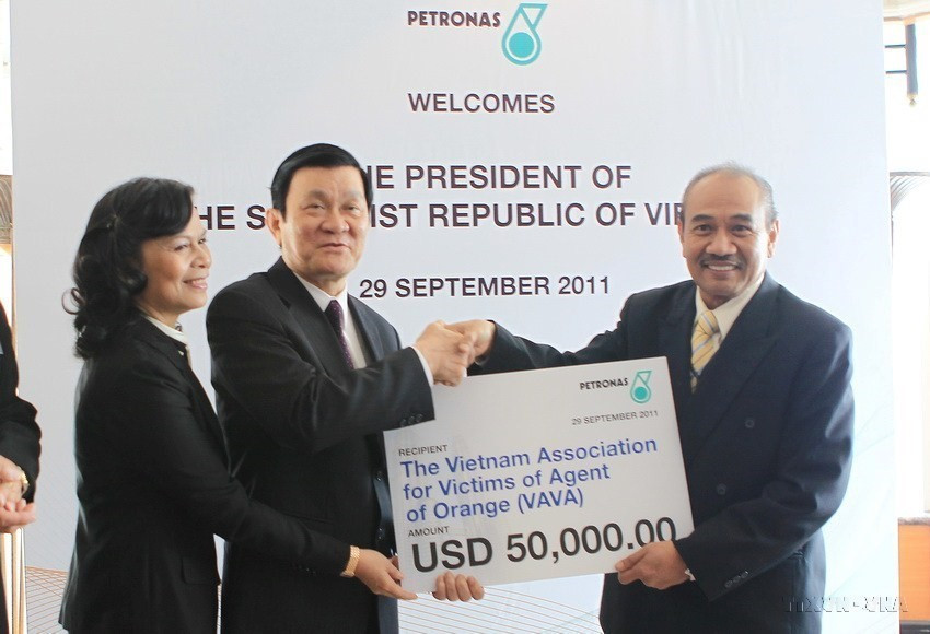 Chủ tịch nước Trương Tấn Sang tiếp nhận 50.000 USD của Tập đoàn Dầu khí Petronas tặng cho nạn nhân chất độc da cam ở Việt Nam trong chuyến thăm cấp Nhà nước tới Malaysia, ngày 28/9/2011. (Ảnh: Nguyễn Khang /TTXVN)
