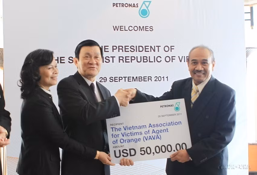 Chủ tịch nước Trương Tấn Sang tiếp nhận 50.000 USD của Tập đoàn Dầu khí Petronas tặng cho nạn nhân chất độc da cam ở Việt Nam trong chuyến thăm cấp Nhà nước tới Malaysia, ngày 28/9/2011. (Ảnh: Nguyễn Khang /TTXVN)