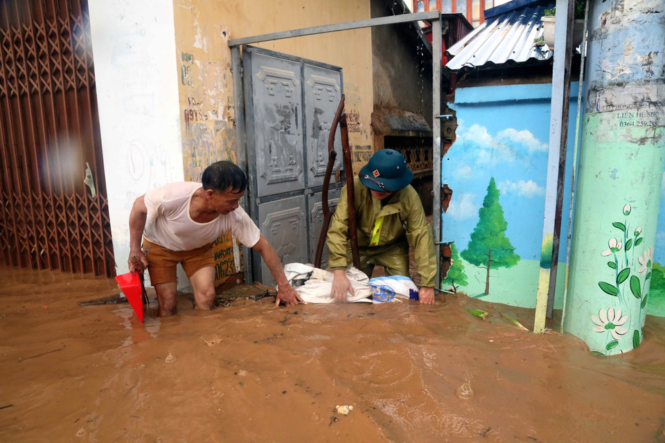 Nhân dân phường Quyết Thắng, thành phố Sơn La che chắn để hạn chế nước chảy vào nhà. (Ảnh: Quang Quyết/TTXVN)