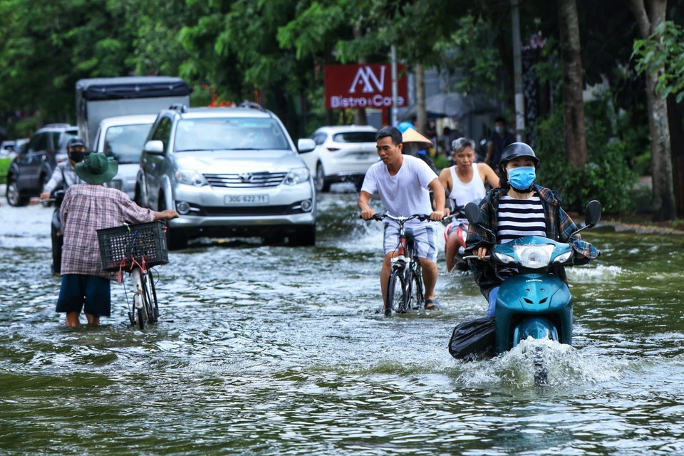 Nước ngập sâu khiến người dân đi lại khó khăn. (Ảnh: Tuấn Anh/TTXVN)