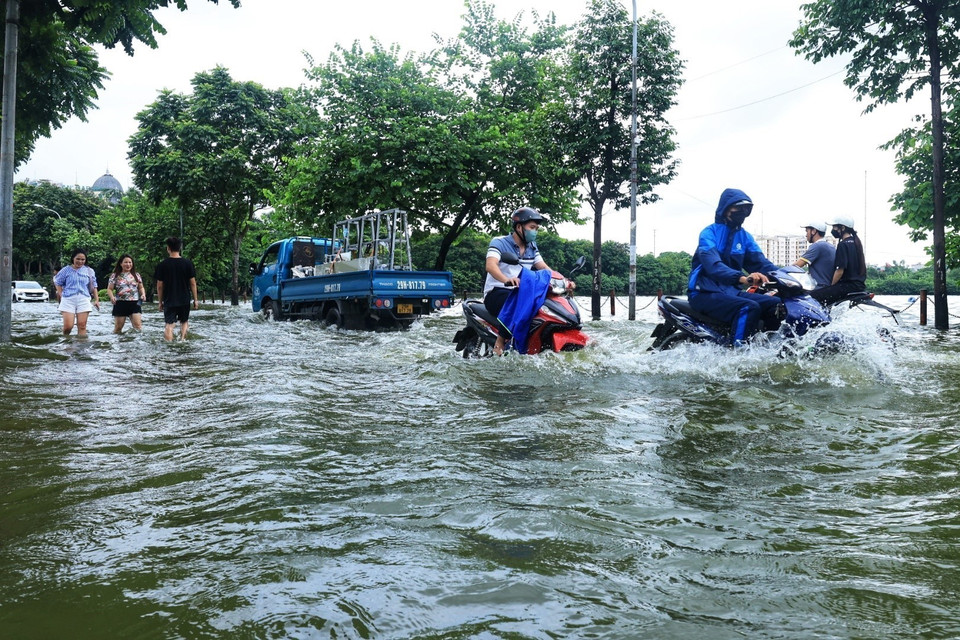 Các phương tiện di chuyển khó khăn khi đi qua chỗ ngập. (Ảnh: Tuấn Anh/TTXVN)