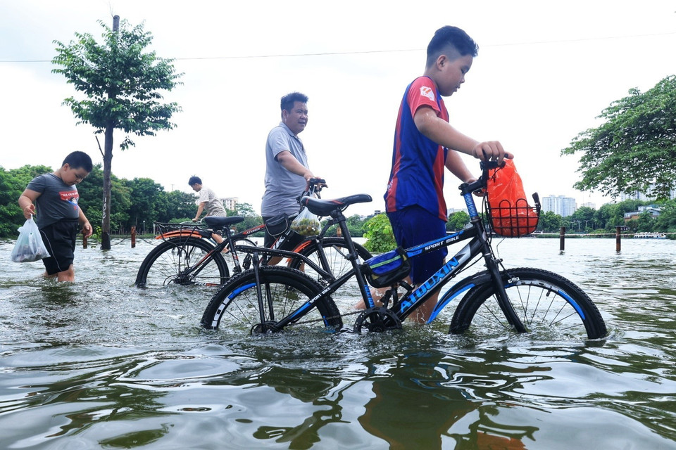 Người dân không thể đạp xe đi qua đoạn đường do nước ngập sâu. (Ảnh: Tuấn Anh/TTXVN)