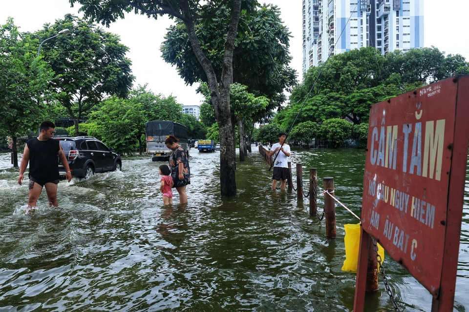 Người dân đứng hướng dẫn các phương tiện khi đi qua chỗ ngập. (Ảnh: Tuấn Anh/TTXVN)