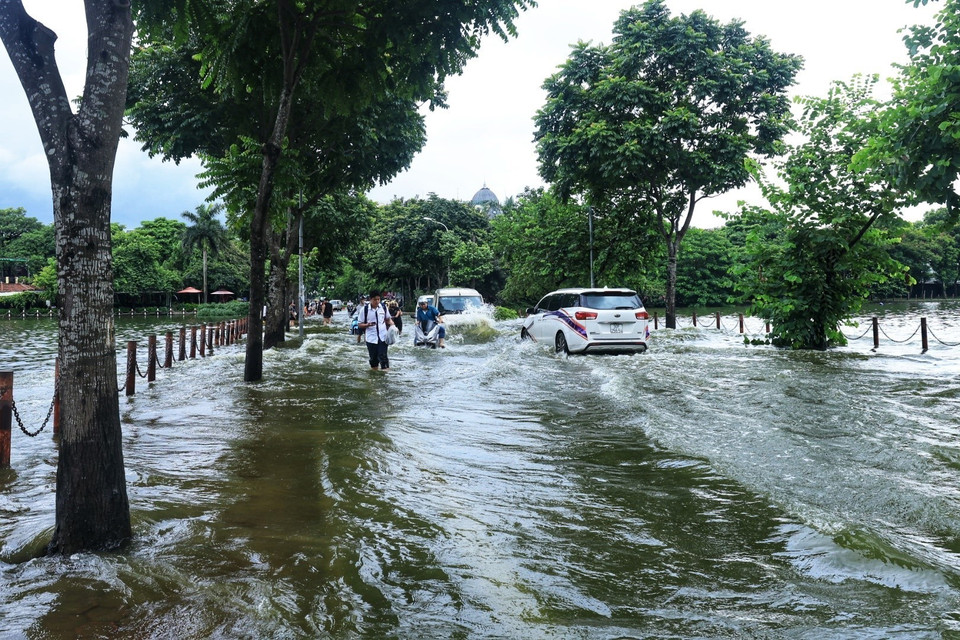 Nước ngập sâu khiến người dân đi lại khó khăn. (Ảnh: Tuấn Anh/TTXVN)