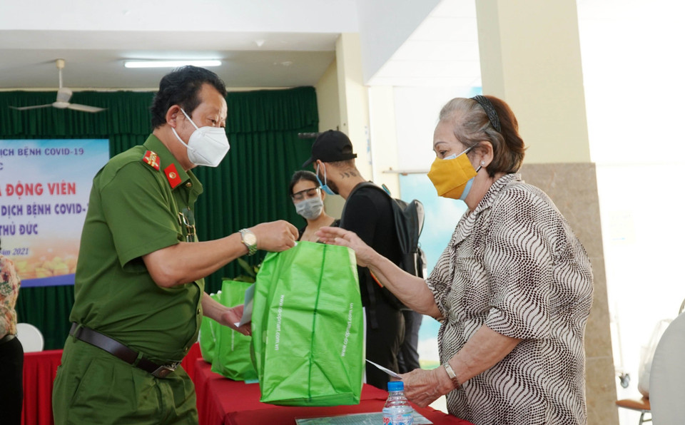 Đại diện Ban Chỉ đạo phòng, chống COVID-19 thành phố Thủ Đức tặng quà động viên người nước ngoài đang lưu trú tại thành phố Thủ Đức. (Ảnh: TTXVN phát)