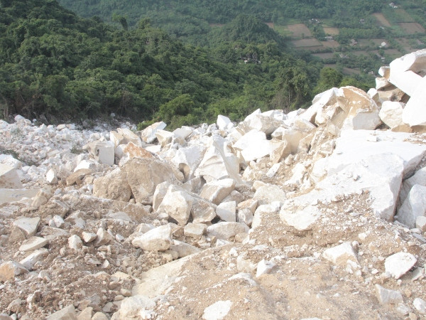 Sau khi lật tung núi, phần đá này sẽ được doanh nghiệp đem vứt ra bãi thải. (Ảnh chụp ở huyện Lục Yên, tỉnh Yên Bái. Hùng Võ/Vietnam+)