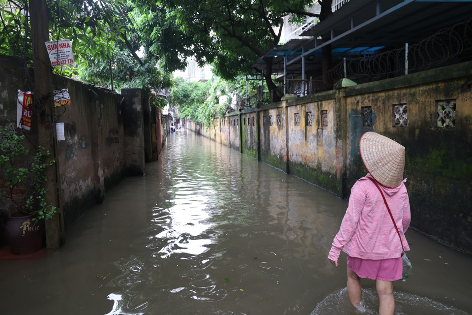 Bà Hoàng Thị Phượng, cư dân ngõ số 2 Cầu Bươu (Thanh Trì, Hà Nội) cho rằng do mực nước sông Nhuệ dâng cao gần bằng mặt đường nên hệ thống thoát nước không tải kịp sau trận mưa lớn từ tối qua 9/9. (Ảnh: Minh Hiếu/Vietnam+)