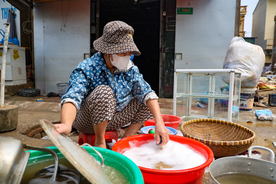 Người dân đang tranh thủ dọn rửa các đồ dùng, vật dụng trong nhà bị ngập úng. (Ảnh: Minh Hiếu/Vietnam+)