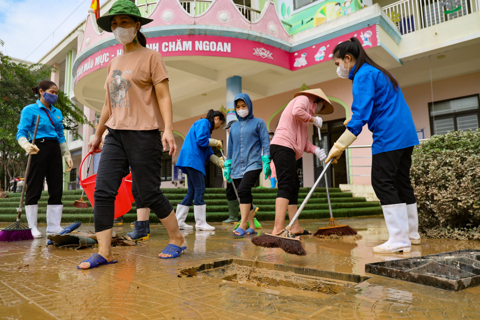 Các cán bộ, giáo viên của các trường trong địa bàn cùng hỗ trợ dọn dẹp, quét sạch rác và bùn đất. (Ảnh: Minh Hiếu/Vietnam+)