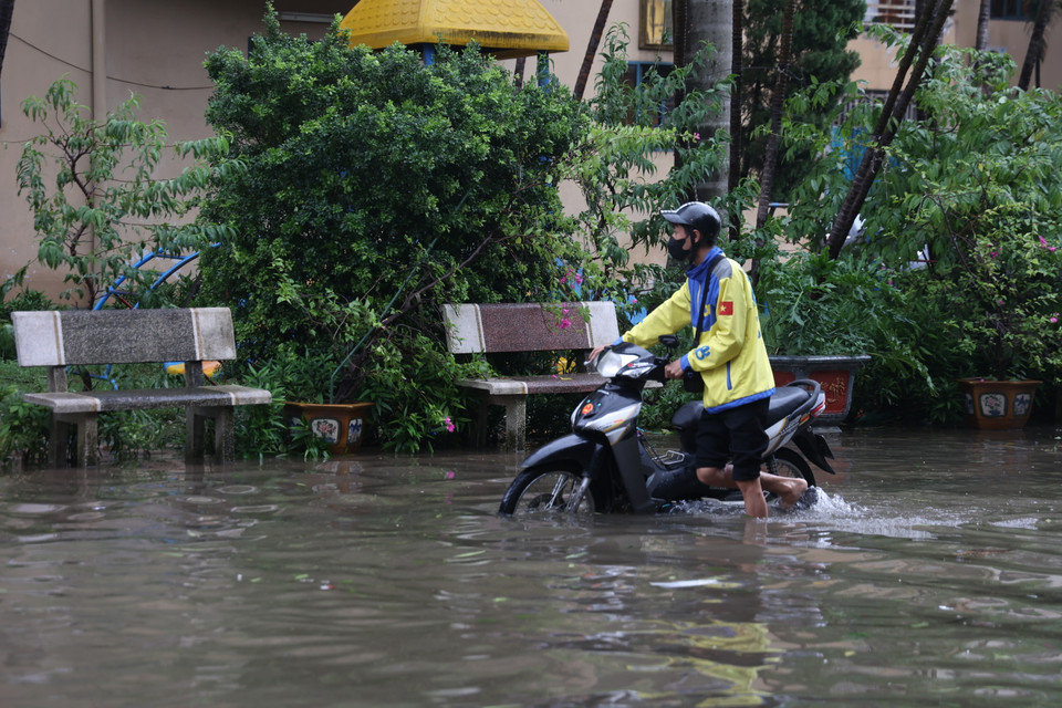 Nước ngập quá sâu khiến một số chủ phương tiện không thể di chuyển và phải dắt bộ. (Ảnh: Minh Hiếu/Vietnam+)