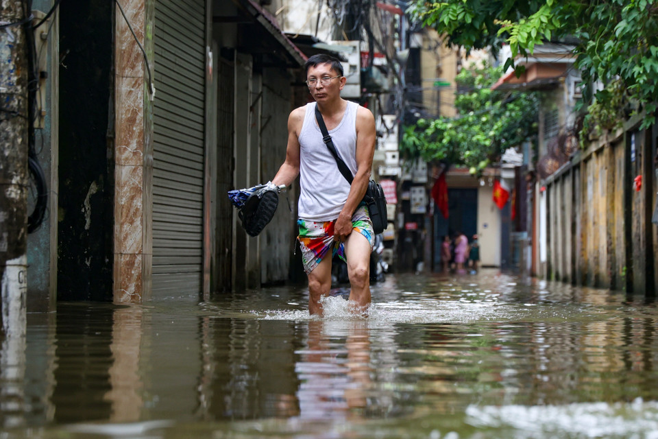 Người dân bì bõm lội nước vào nhà. (Ảnh: Minh Hiếu/Vietnam+)