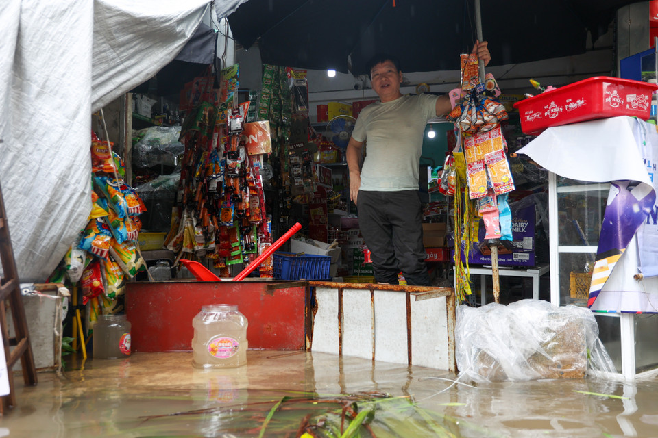 Một số hộ dân, hộ kinh doanh thực hiện một số biện pháp để che chắn nước không tràn vào nhà. (Ảnh: Minh Hiếu/Vietnam+)