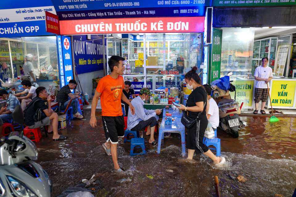 Nước ngập lên cả vỉa hè khiến người dân buôn bán, sinh hoạt xung quanh các hàng quán cũng bị ảnh hưởng. (Ảnh: Minh Hiếu/Vietnam+)