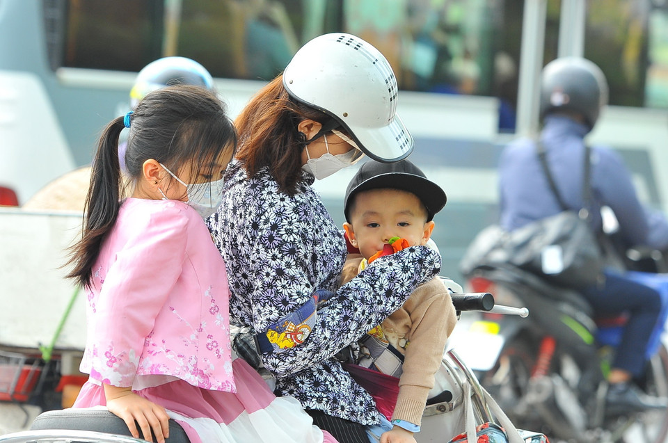 Một phụ nữ dừng nghỉ bên đường để cho con uống nước. (Ảnh: Minh Đức/TTXVN)