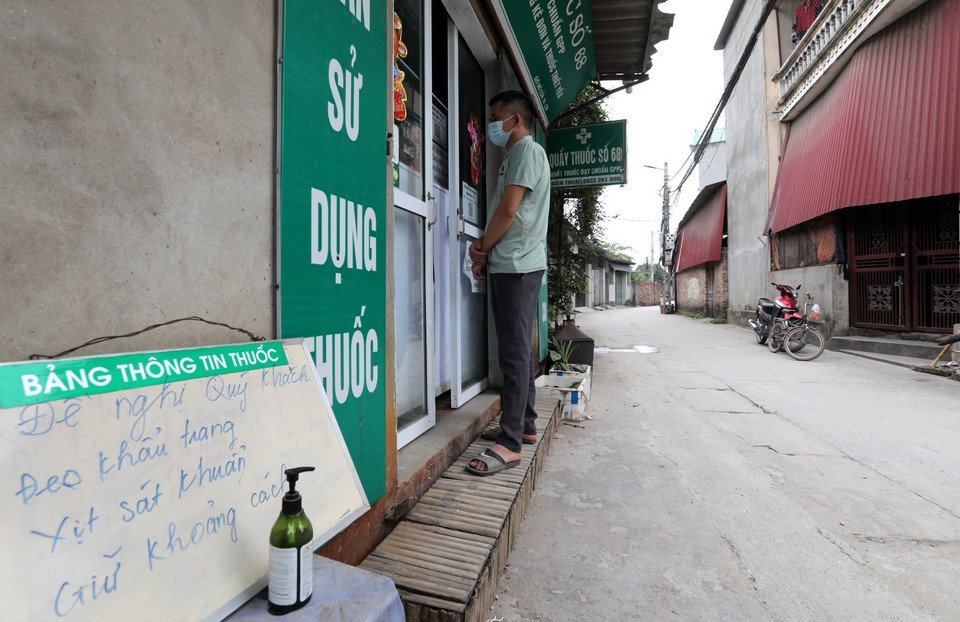 Người dân thôn Lỗ Giao (xã Việt Hùng, huyện Đông Anh) mua thuốc phải đeo khẩu trang, đứng giãn khoảng cách đúng quy định. (Ảnh: Thành Đạt/TTXVN)