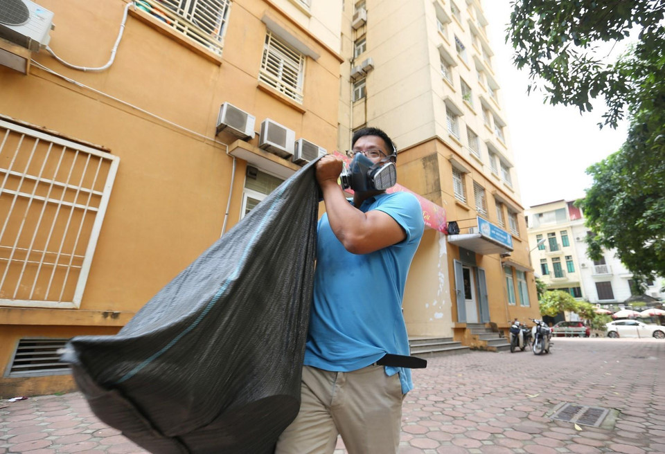 Người dân cẩn thận đeo mặt nạ chống độc khi chuyển đồ đạc. (Ảnh: Thành Đạt/TTXVN)