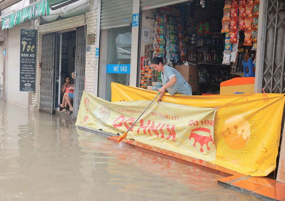 Người dân phố Vạn Kiếp, quận Hai Bà Trưng dọn dẹp, vệ sinh nhà cửa khi nước bắt đầu rút (ảnh chụp lúc 8h30). (Ảnh: Hoàng Hiếu/TTXVN)