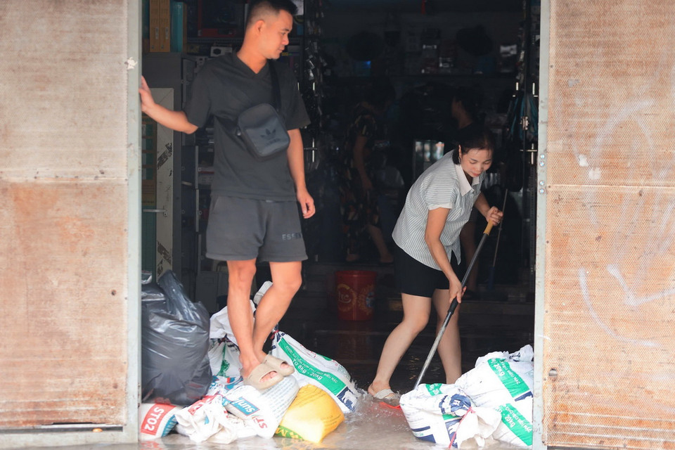 Người dân phố Vạn Kiếp, quận Hai Bà Trưng dọn dẹp, vệ sinh nhà cửa khi nước bắt đầu rút (ảnh chụp lúc 8h30). (Ảnh: Hoàng Hiếu/TTXVN)