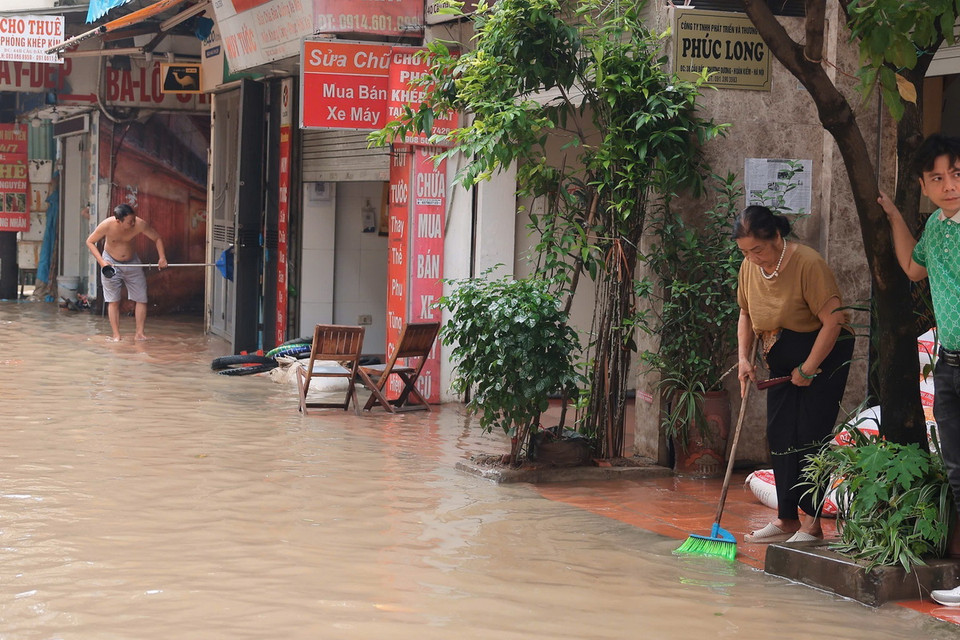 Người dân phố Vạn Kiếp, quận Hai Bà Trưng dọn dẹp, vệ sinh nhà cửa khi nước bắt đầu rút (ảnh chụp lúc 8h30). (Ảnh: Hoàng Hiếu/TTXVN)