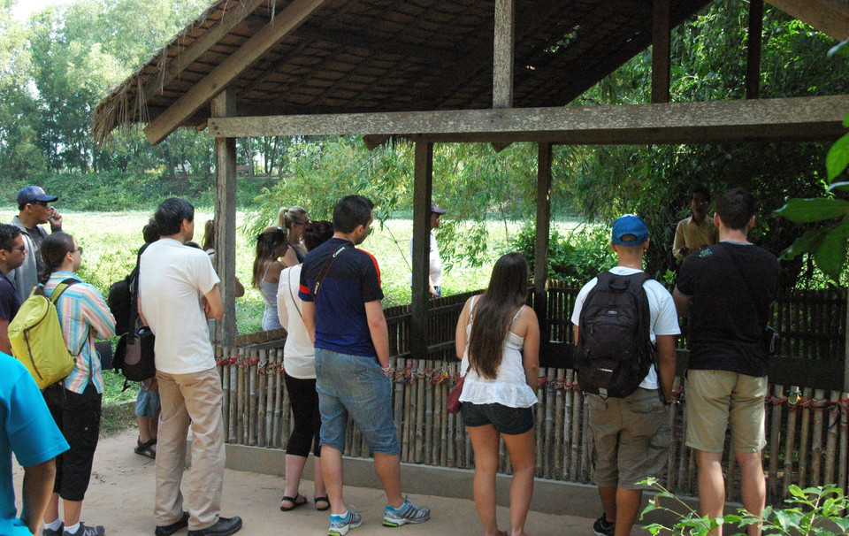 Du khách nghe giới thiệu về hố chôn người tập thể. (Ảnh: Xuân Khu/Vietnam+)