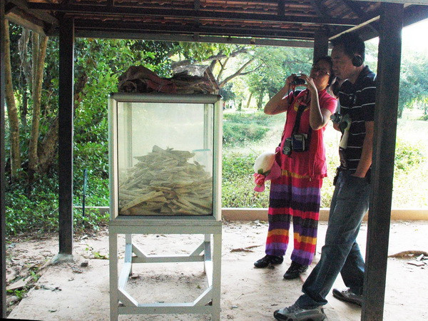Du khách chụp ảnh hộp chứa xương cốt nạn nhân Khmer Đỏ tại Choueng Ek. (Ảnh: Xuân Khu/Vietnam+)