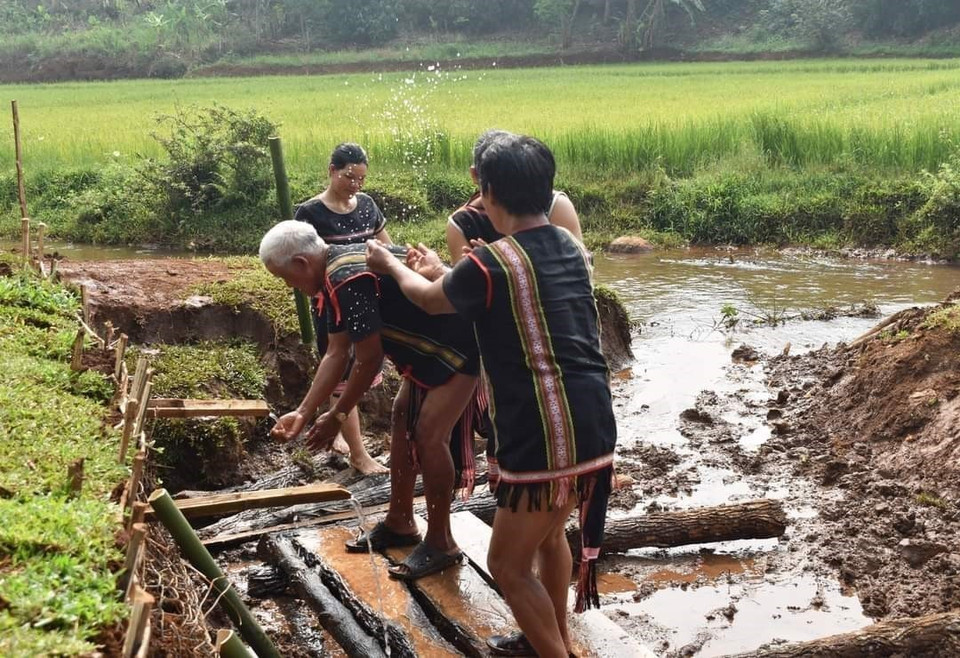 Sau lễ cúng, người dân trong làng cùng xuống giọt nước để thực hiện các nghi thức cầu may mắn. (Ảnh: TTXVN phát)